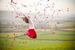 Girl jumping with rose petals in air